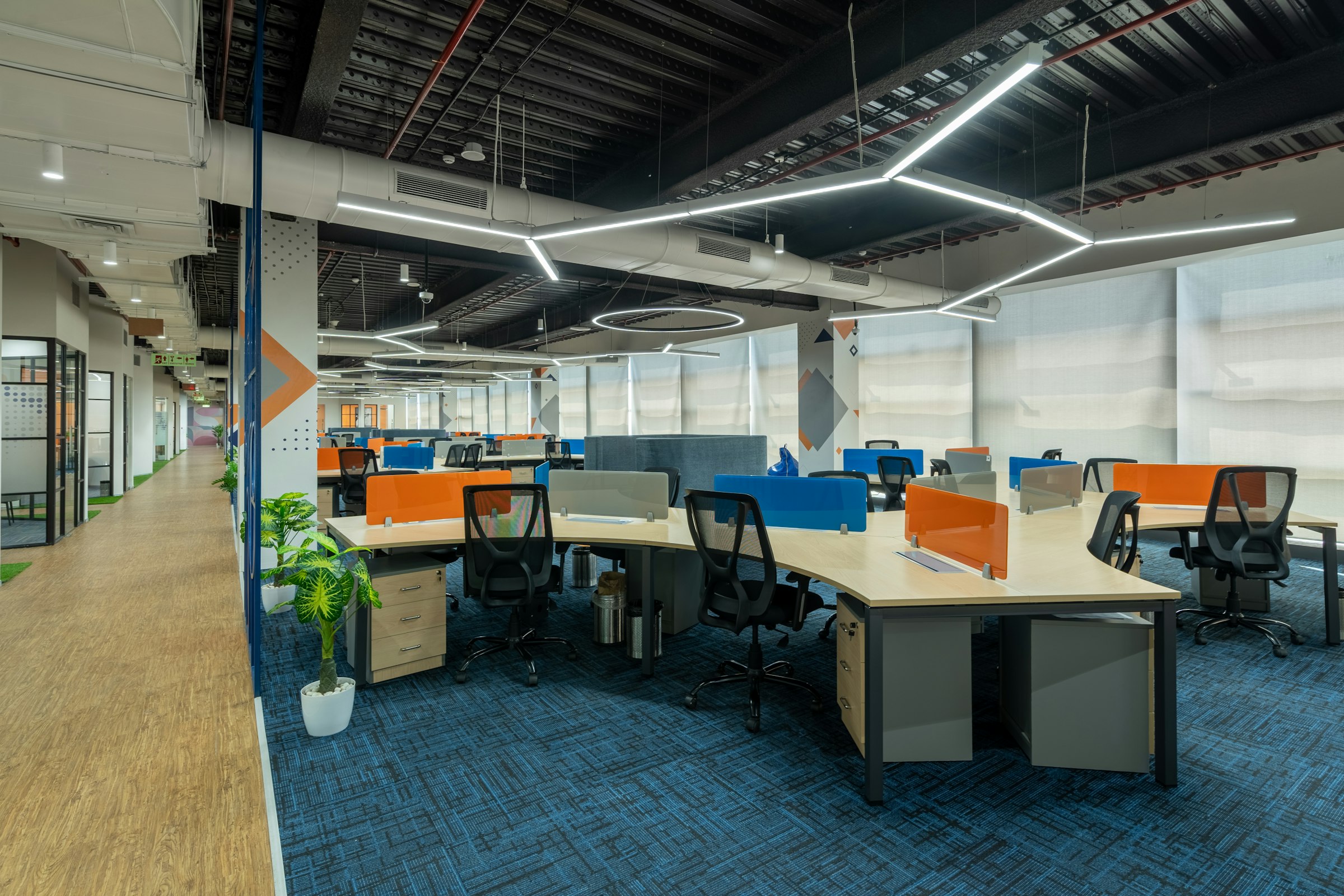 A large open-plan office floor with shared desks and soft seating